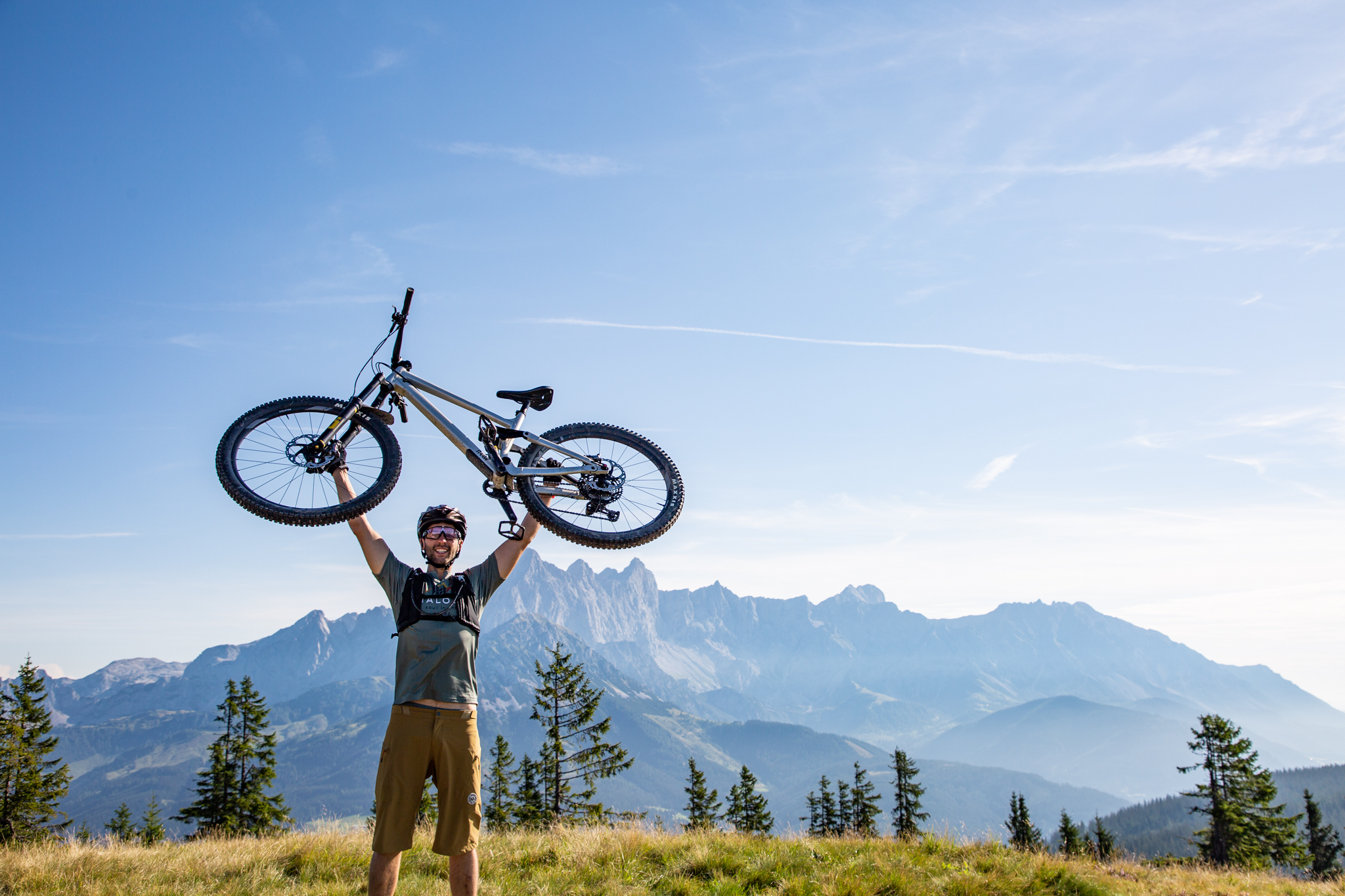 Der Stoneman Taurista, die MTB-Challenge in der Salzburger Sportwelt und Obertauern. Auf dem Bild sieht man einen Mountainbiker, der sein Rad aus lauter Freude die Herausforderung geschafft zu haben am Rossbrandgipfel in Radstadt in die Höhe stemmt.